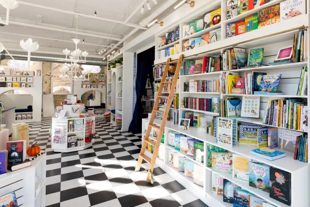A white-painted bookshop with different kinds of book displays with black and white chessboard flooring.